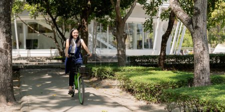Foto de Empresaria asiática en bicicleta ir a trabajar en la oficina. Transporte en bicicleta, mujer de negocios feliz utilizando el transporte ecológico, concepto de estilo de vida ecológico. - Imagen libre de derechos