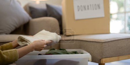 Photo for Donation, asian young woman sitting pack object at home, putting on stuff into donate box with second hand clothes, charity helping and needy people. Reuse recycle. - Royalty Free Image