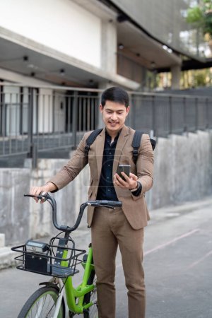 Hombre de negocios asiático en un traje está montando una bicicleta en las calles de la ciudad para su viaje de la mañana al trabajo. Concepto de transporte ecológico, concepto de estilo de vida sostenible.