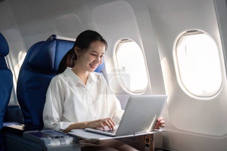 Foto de Éxito joven mujer de negocios asiática se sienta en avión cabina avión y trabajando desde cualquier lugar. Volando en primera clase. - Imagen libre de derechos