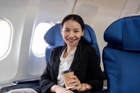 Foto de Retrato de una exitosa empresaria asiática sonriente o empresaria con traje formal en un avión se sienta en un asiento de clase ejecutiva durante el vuelo. - Imagen libre de derechos