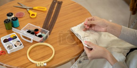 Photo for Woman repairs sews reuses fabric from old clothes economical reuse. DIY Hobby Reuse Recycling at home. - Royalty Free Image