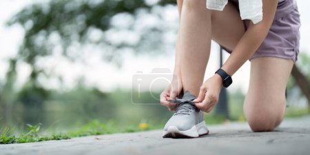 Téléchargez les photos : Femme attachant des lacets de chaussures. Gros plan de coureuse de fitness sportive se préparant pour le jogging en plein air sur le parc. - en image libre de droit