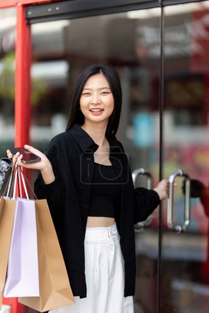 Photo for Cheerful Beautiful Asian woman holding shopping bags in shopping in the city on holiday Black Friday. - Royalty Free Image