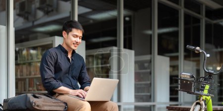 Téléchargez les photos : Homme d'affaires asiatique avec vélo à l'aide d'un ordinateur portable et assis à l'extérieur du bâtiment de bureaux. homme qui fait la navette à vélo aller au travail. Véhicule écologique, concept de mode de vie durable. - en image libre de droit