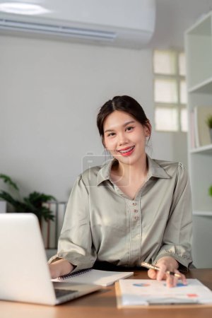 Geschäftsfrau mit Laptop und Taschenrechner arbeitet zu Hause mit Taschenrechner-Dokument auf dem Schreibtisch, Finanzanalysekonzept.