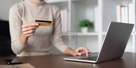 Foto de Mujer joven sosteniendo tarjeta de crédito utilizando el pago del ordenador portátil en casa. Compras de cliente femenino haciendo compra en línea en el ordenador portátil. - Imagen libre de derechos