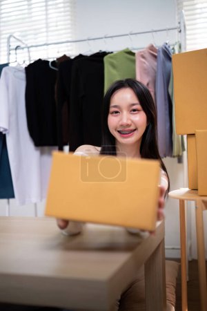 Foto de Feliz joven asiática mujer startup pequeña empresa freelance holding parcel box. concepto de entrega de caja de embalaje de marketing en línea. - Imagen libre de derechos