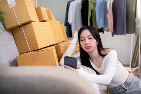 Foto de Mujer asiática siente estrés de preocupación y dolor de cabeza durante la espera de un nuevo pedido de negocio en casa cliente en línea. - Imagen libre de derechos
