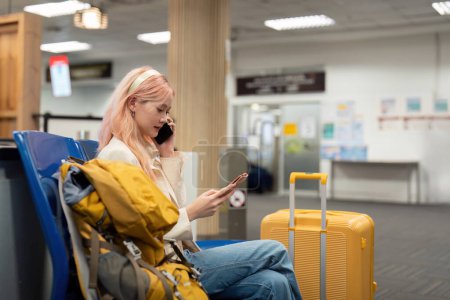 Photo for Asian woman sitting in waiting room and talking over smartphone. woman travel talking on cell phone at airport lounge. Successful woman on mobile phone at terminal. - Royalty Free Image