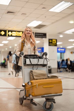 Téléchargez les photos : Heureuse femme touristique asiatique avec sac à dos et bagages voyageant entre les attentes pour le vol dans le terminal de l'aéroport, concept de voyage touristique. - en image libre de droit