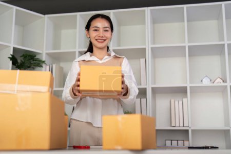 Photo for Young woman working online ecommerce shopping at her shop. Young woman sell prepare parcel box of product for deliver to customer. Online selling, ecommerce. Selling products online. - Royalty Free Image