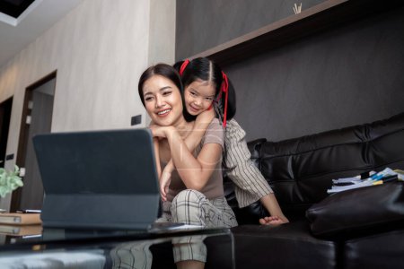 Photo for Cute active naughty girl noisy child plays with mom hugs mother attention from mom. woman work on laptop at home. - Royalty Free Image