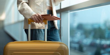 Téléchargez les photos : Main de la passagère titulaire d'un passeport avec le vol dans l'aérogare. - en image libre de droit