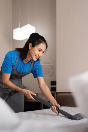 Photo for Cleaning service employee removing dirt from with professional equipment. Female housekeeper cleaning the mattress on the bed with vacuum cleaner. - Royalty Free Image