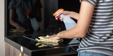Foto de Mujer asiática limpiando la superficie de la mesa con toalla y detergente en aerosol. - Imagen libre de derechos
