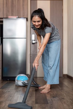 Photo for Young woman asian cleaning floor with vacuum cleaner in living room, Housework, cleanig and chores concept. - Royalty Free Image
