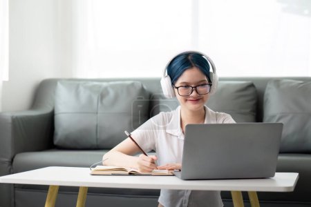 Photo for Happy young woman teenage wearing headphones writing note. student online learning class study online video call zoom teacher with laptop and book. - Royalty Free Image