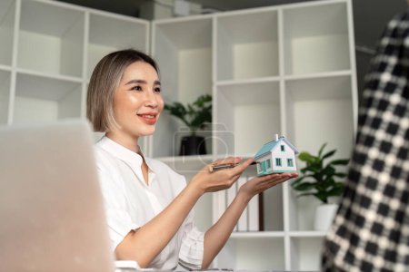 Hausverkauf und Hausversicherungs-Konzept, Immobilienmakler mit Hausmodell im Gespräch mit dem Kunden über den Kauf von Hausversicherungen und Unterzeichnung des Vertrages unter formeller Vertragsvereinbarung.
