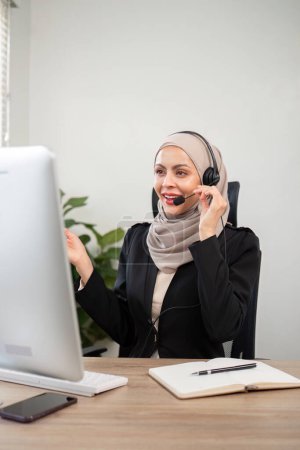 Téléchargez les photos : Jeunes femmes musulmanes portant du télémarketing hijab ou un agent du centre d'appels avec un casque travaillant sur la hotline de soutien au bureau. - en image libre de droit