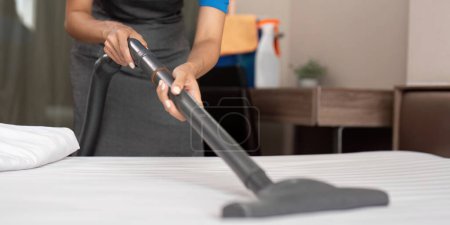 Photo for Cleaning service employee removing dirt from with professional equipment. Female housekeeper cleaning the mattress on the bed with vacuum cleaner. - Royalty Free Image