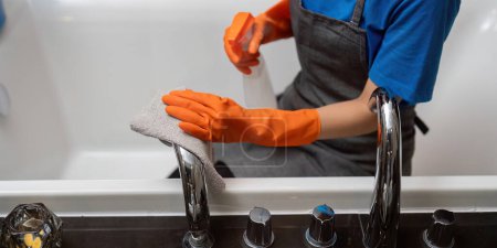 Foto de Empresa de servicios de limpieza profesional empleada en guantes de goma limpieza y spray detergente en baño. - Imagen libre de derechos
