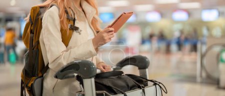 Photo for Hand of woman passenger holding passport with the flight in airport terminal. - Royalty Free Image