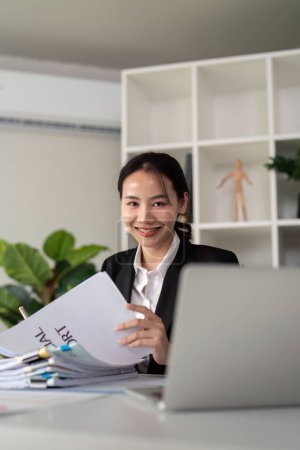 Photo for Young business woman asian or employee accounting bookkeeping documents checking financial data or marketing report working in office with laptop. Paperwork management. - Royalty Free Image