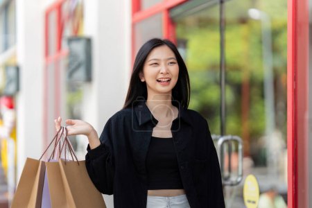 Photo for Cheerful Beautiful Asian woman holding shopping bags in shopping in the city on holiday Black Friday. - Royalty Free Image