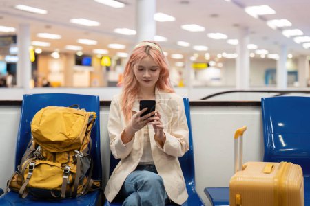 Photo for Happy asian tourist woman using mobile smartphone with suitcase traveling between waits for flight in Airport Terminal, flight check in, Tourist journey trip concept. - Royalty Free Image