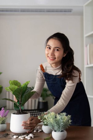 The concept of eco friendly housing, plant care and gardening. Preparing garden. Relax home gardening. Gardener woman asian hand planting flower in pot. Smiling woman takes care of plant.
