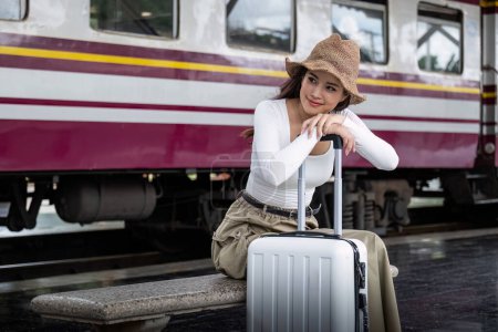 Téléchargez les photos : Jeune femme asiatique assise et attendant que le train attende pour aller voyager. Concept de voyage. - en image libre de droit