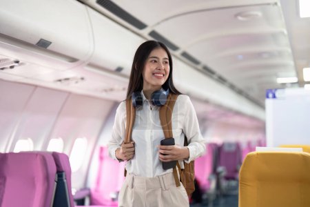 Téléchargez les photos : Seule femme asiatique voyageant en avion. heureux voyageur à bord. Concept de voyage solo. - en image libre de droit