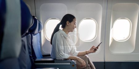 Foto de Éxito joven mujer de negocios asiática se sienta en avión cabina avión y trabajando desde cualquier lugar. Volando en primera clase. - Imagen libre de derechos