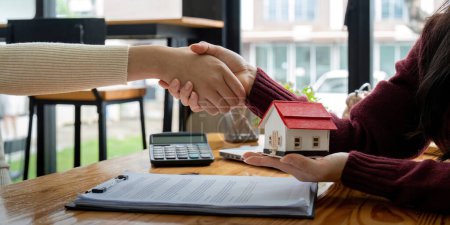 Téléchargez les photos : Agent immobilier et client serrant la main après le contrat fini après environ assurance habitation et prêt à l'investissement. - en image libre de droit