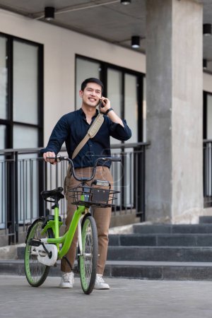Foto de Eco amigable, feliz estilo de vida asiático joven hombre de negocios montar en bicicleta ir a la oficina de trabajo en la calle de la ciudad con bicicleta en la mañana. - Imagen libre de derechos