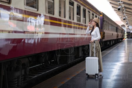 Photo for Alone Asian woman traveler with suitcase in train station platform. Summer vacation holiday and travel concept. - Royalty Free Image