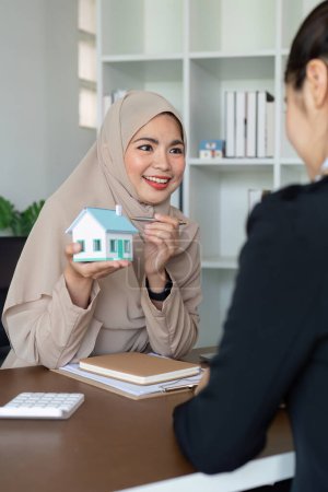 Téléchargez les photos : Femme musulmane agent immobilier et client discutant achat de maison, assurance, prêt hypothécaire ou prêt immobilier d'investissement. - en image libre de droit