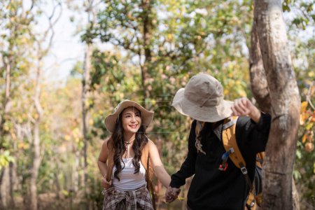 Téléchargez les photos : Gai romantique lesbienne couple voyageur avec sac à dos sur leur dos aller randonnée à travers la forêt dans les montagnes en été. - en image libre de droit