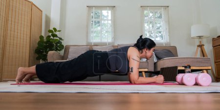 Photo for Asian overweight woman doing stretching exercise at home on fitness , online fitness class. Stretching training workout on yoga mat at home for good health and body shape. - Royalty Free Image