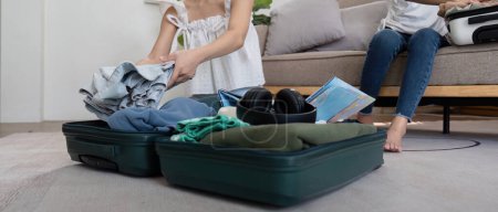 Photo for Friends and travel. Two asian young woman friends packing a travel bag before going on holidays. - Royalty Free Image
