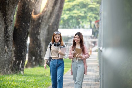 Foto de Estudiante universitaria amiga de aprender libro universidad mientras camina en el campus. - Imagen libre de derechos