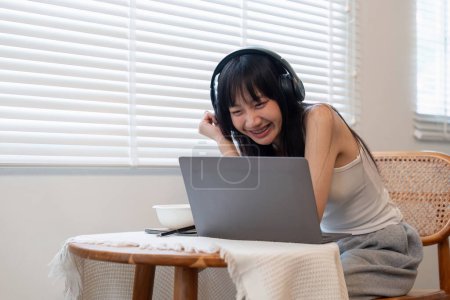 Téléchargez les photos : Jeune femme utilisant un ordinateur portable et portant un casque à la maison. - en image libre de droit