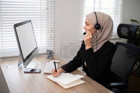Téléchargez les photos : Jeunes femmes musulmanes portant du télémarketing hijab ou un agent du centre d'appels avec un casque travaillant sur la hotline de soutien au bureau. - en image libre de droit