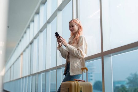 Foto de Una mujer asiática caminando en un aeropuerto. Móvil, maleta y viajar con una mujer joven en un viaje de trabajo o de viaje. - Imagen libre de derechos