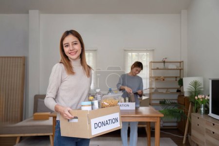 Foto de Mujer con caja de caridad y grupo de voluntarios en el centro de asistencia. Caridad, donación y concepto de voluntariado. - Imagen libre de derechos