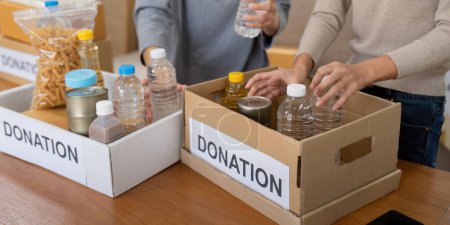 Photo for Group of volunteer woman working in home. Happy volunteer looking at food donation box separating donations stuffs. - Royalty Free Image