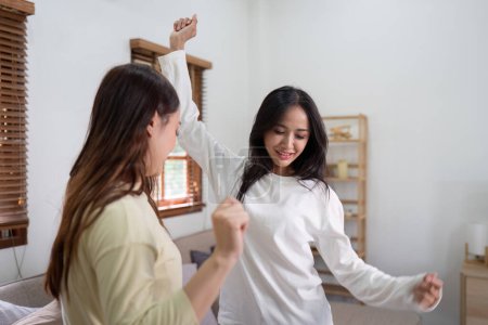 Photo for Lesbian asian couple dancing with each other while resting at the living room. - Royalty Free Image
