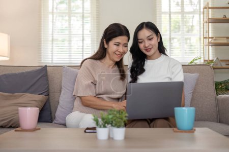 Photo for Happy mother and adult daughter use laptop having fun, sitting on couch at home, smiling woman embracing older mum, spending leisure time together. for Happy mothers day. - Royalty Free Image