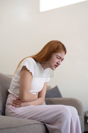 Photo for Asian woman having painful from stomach ache at home, Female suffering with abdominal pain. - Royalty Free Image